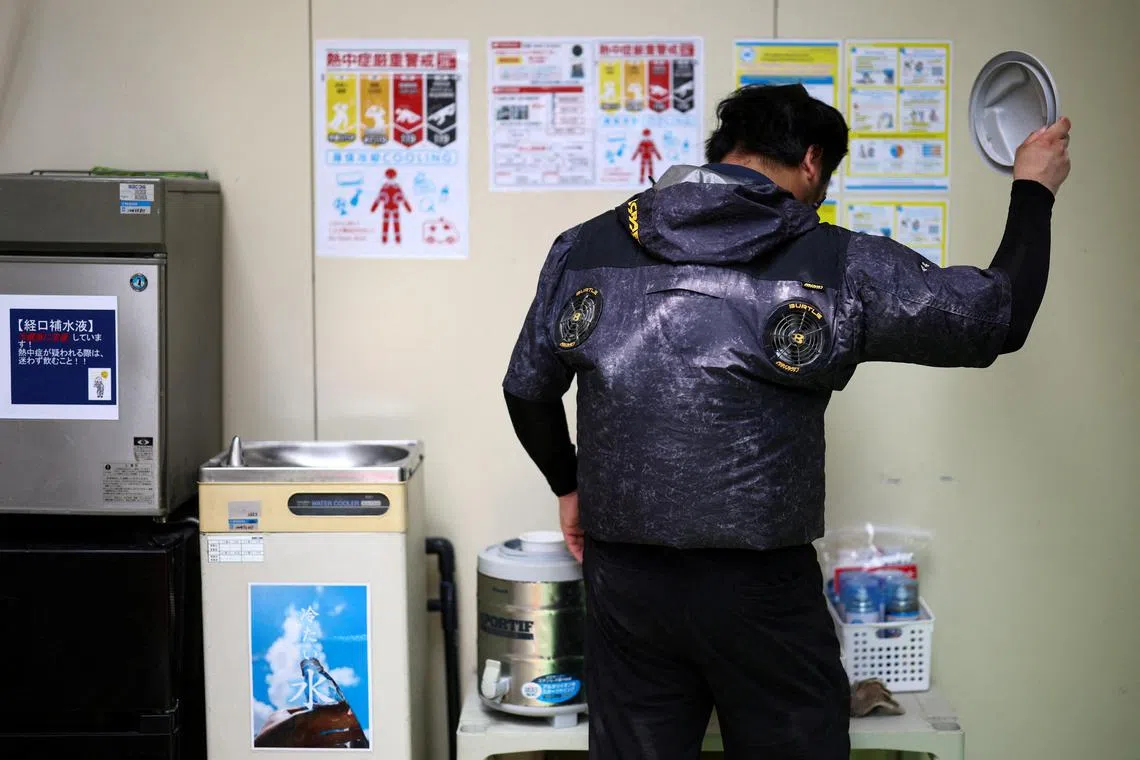 日本政府上个月向东京和其他县市发布中暑警报，一名工人身穿带有冷却风扇的空调夹克在一栋在建的公寓楼内休息。（路透社）