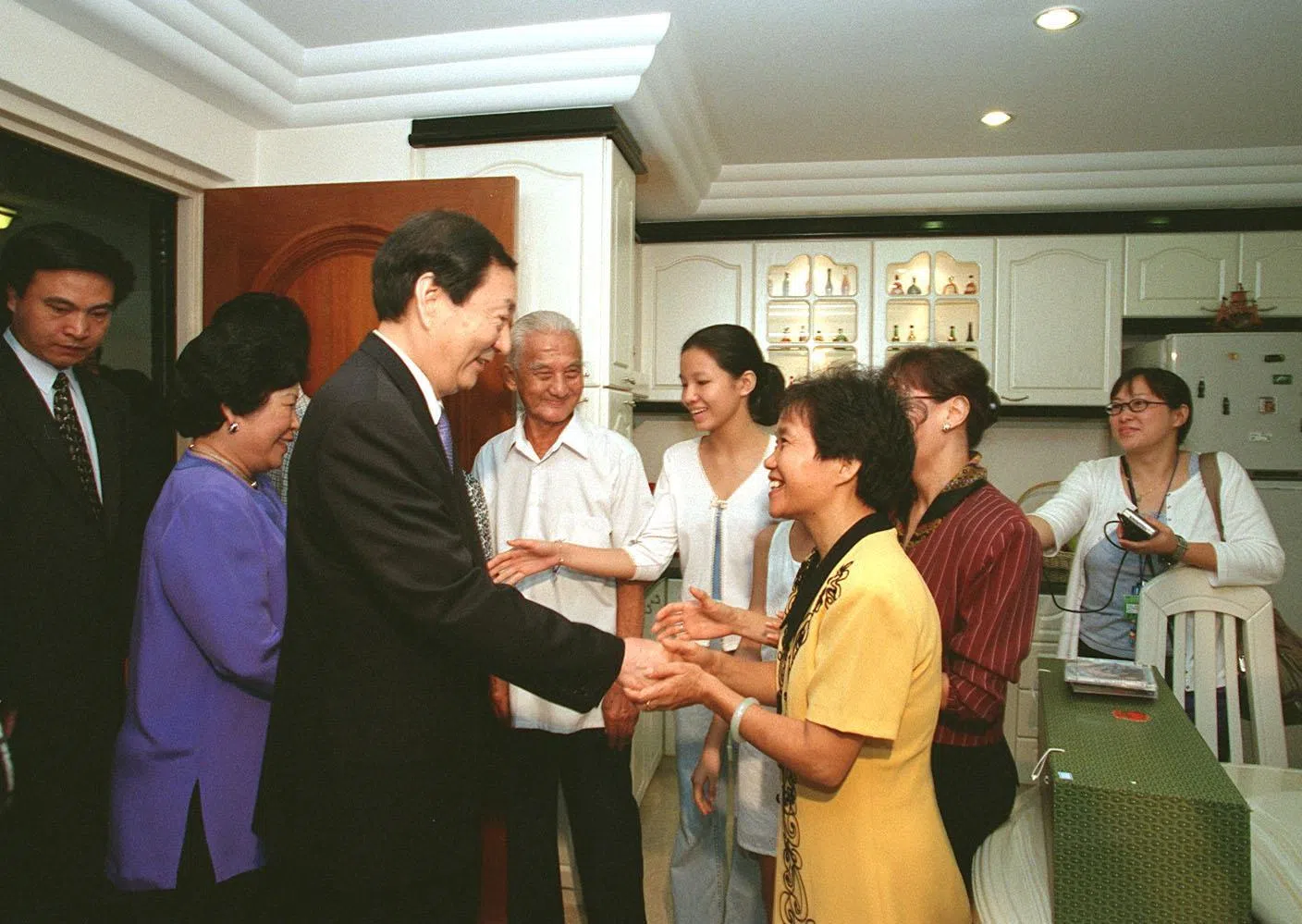朱镕基（左三）1999年访问我国期间，曾与夫人劳安（左二）一起参观大巴窑组屋区，并走入三户本地家庭的住家作客，了解新加坡人的日常生活。图为朱镕基在大巴窑4巷第81座组屋参观时，与屋主邓伟华一家人亲切互动。（档案照片）