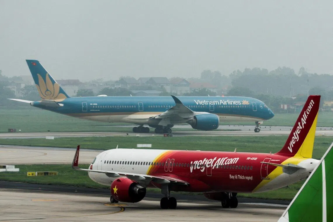 在越南河内内排国际机场，越捷航空公司的一架飞机在越南国家航空公司的飞机前方滑行。（路透社）
