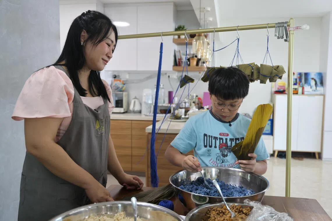 蔡常威之前看妈妈朱美玲（左）和奶奶包粽子，在耳濡目染下，也学会这门手艺。（张俊杰摄）