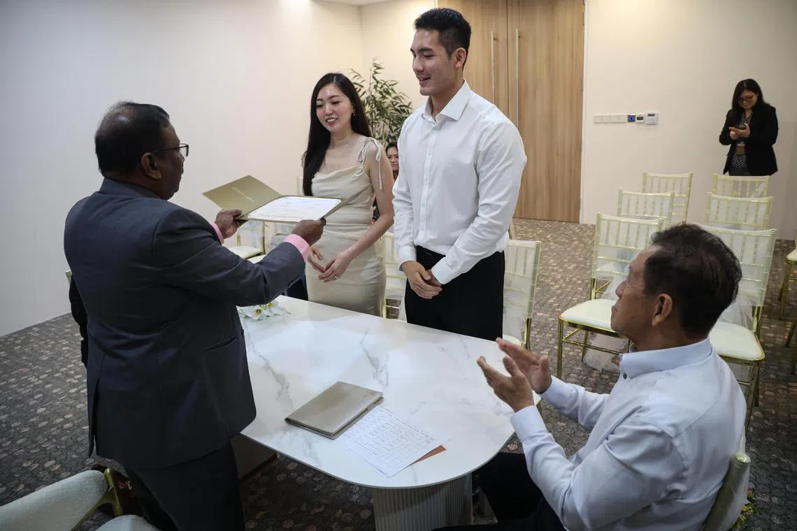 黄炳耀和许彩霞在家人见证下签字结婚，成为第一对在临时地点注册结婚的新人。（关俊威摄）