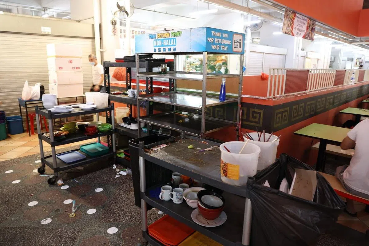 托盘归还处附近的地板上堆积了垃圾，有用过的纸巾、塑料包装袋以及一次性餐具等。