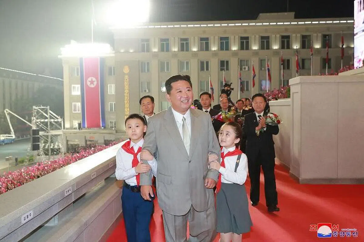 金正恩当天深夜抵达平壤金日成广场，两名儿童挽着他的手臂。（朝中社）