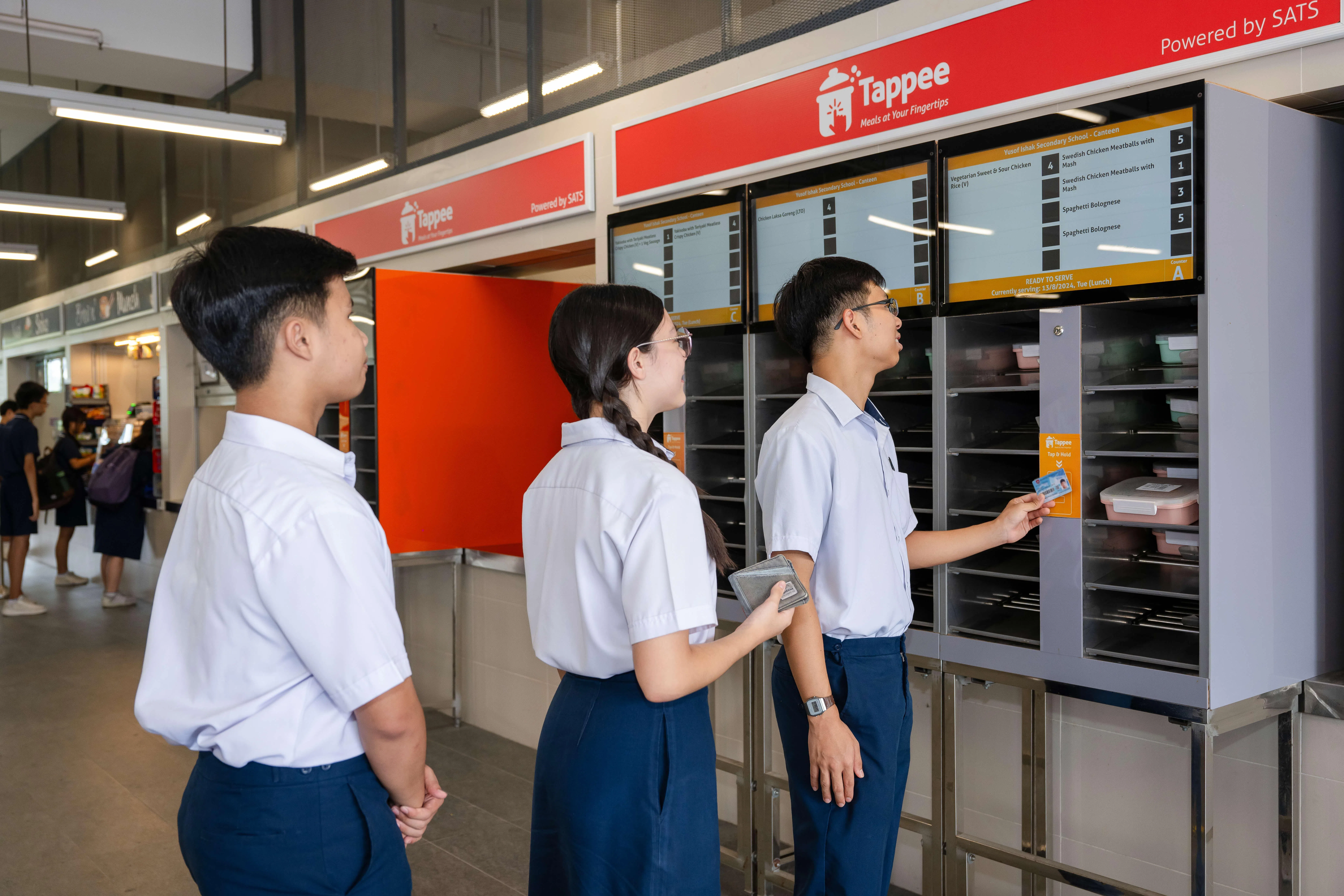 尤索夫依萨中学学生，在取餐机前以学校智慧卡领取他们预先订好的餐食。（教育部提供）