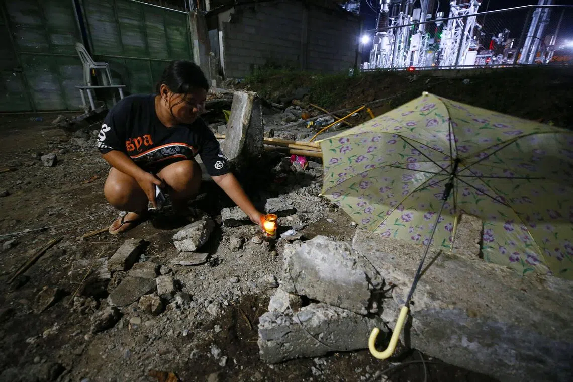 在菲律宾马蒂市，一人因被倒塌的墙体砸中身亡，死者亲属在事发场所点蜡烛悼念。（法新社）