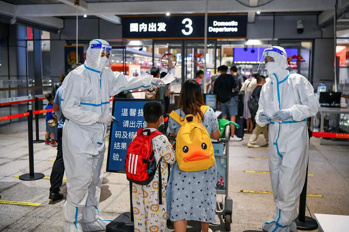今年8月，旅游大省海南疫情爆发，数千名游客滞留。图为8月11日的三亚机场，身穿防护服的工作人员在核对旅客信息。（路透社）