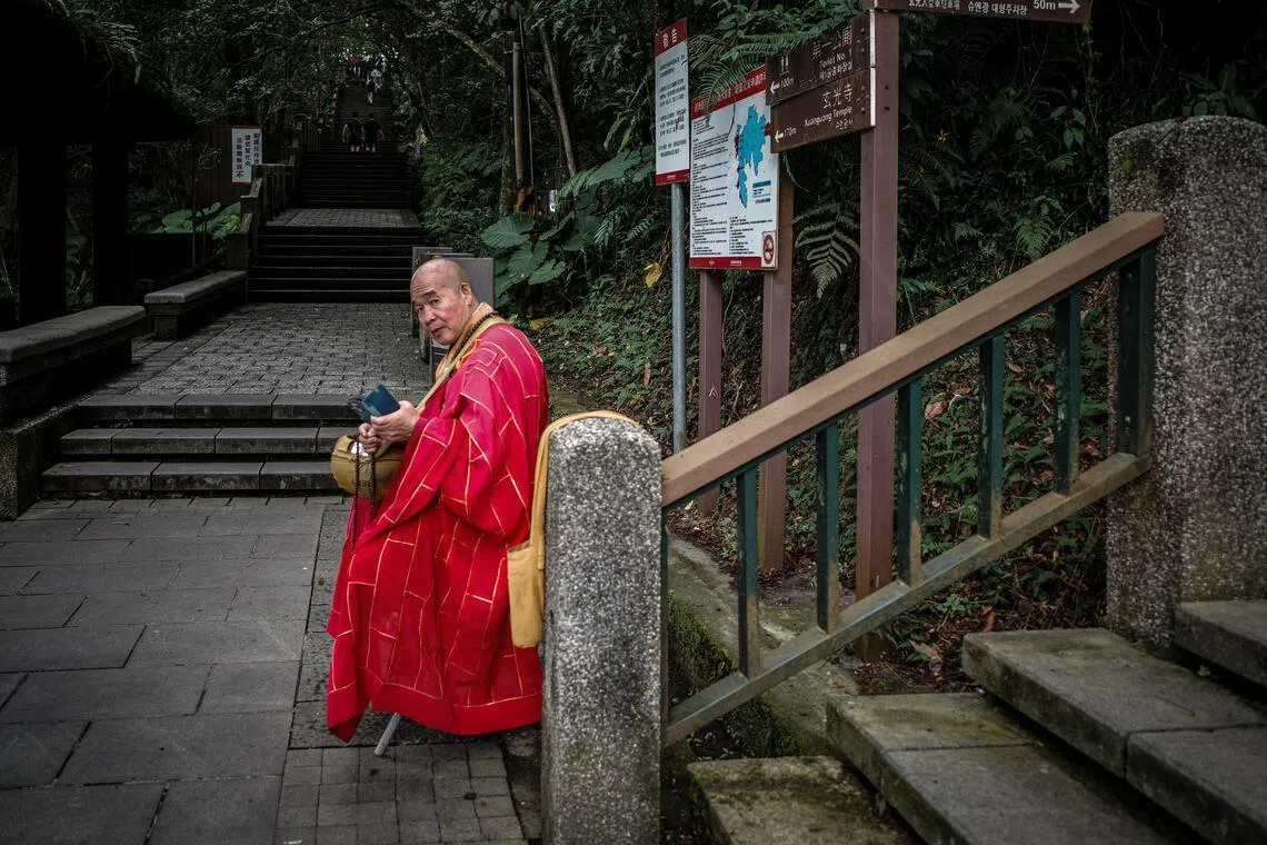 日月潭的石阶旁，一抹红袍在翠绿山林间，静默如禅。（叶振忠摄）
