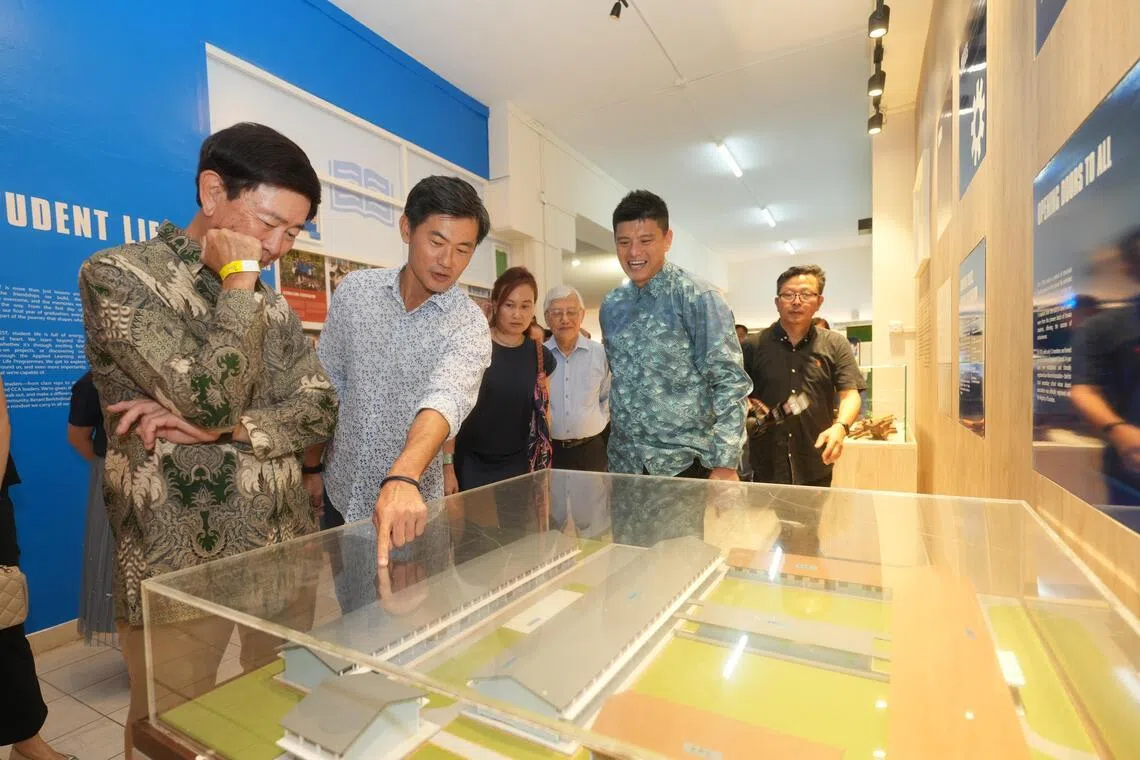 总理公署高级政务部长兼全国职工总会副秘书长陈国明（左二）、SUTL总裁郑登源（左一）都是女皇镇中学的校友。他们都参加了母校70周年的校庆活动，一同参观校史长廊。（谢智扬摄）