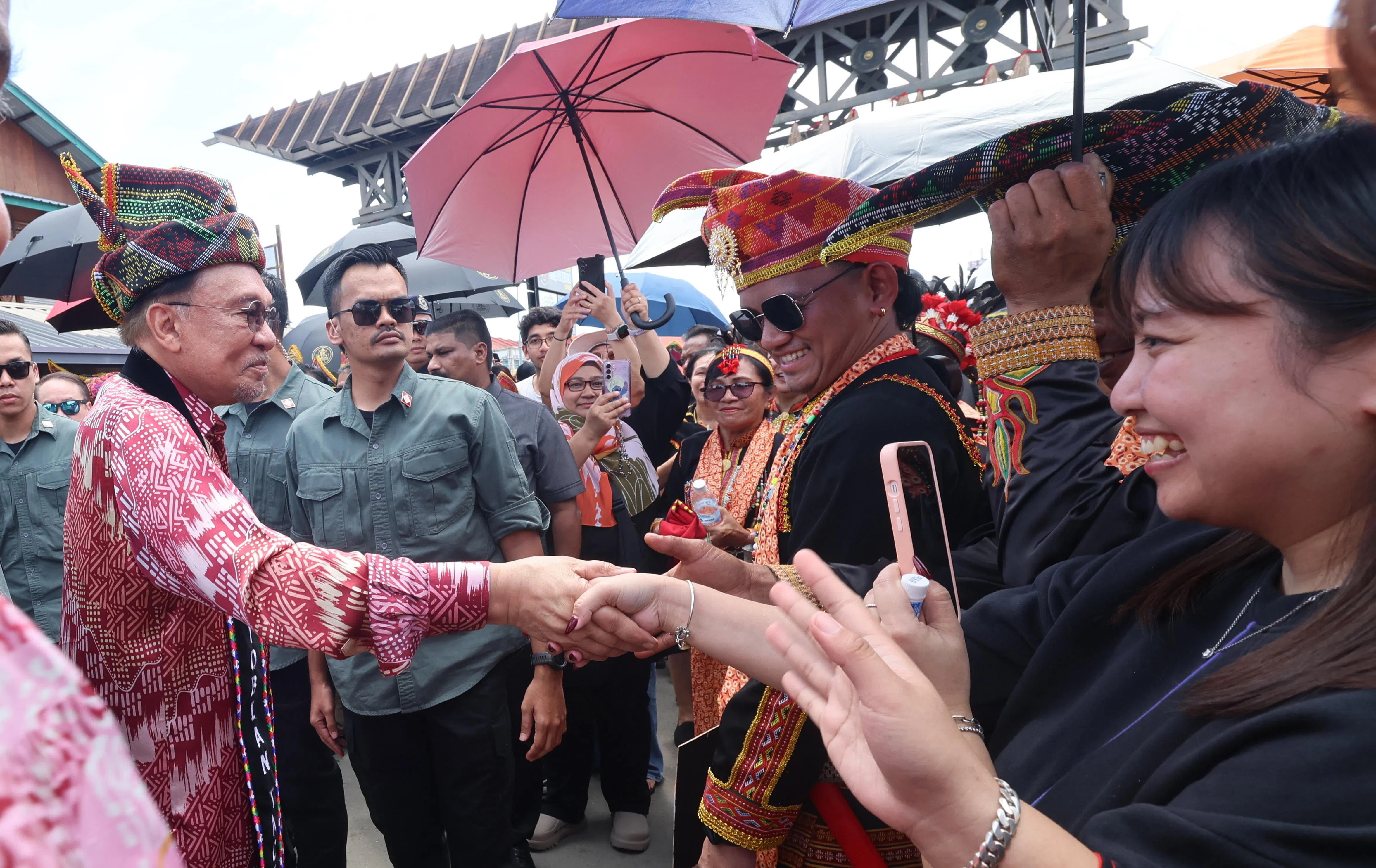马来西亚首相安华（左）佩戴沙巴原住民的传统服饰，与当地民众共庆丰收节。（马新社）