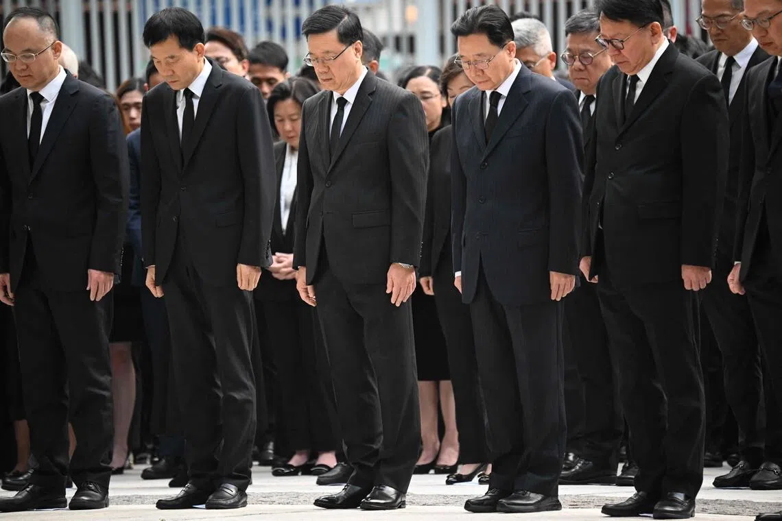 香港特首李家超（中）联同主要官员、行政会议非官守议员及公务员代表早上8时在政府总部东翼前地默哀。（法新社）