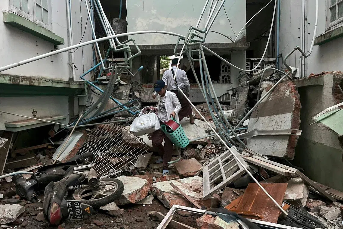 地震过后，内比都居民在倒塌房屋的废墟上捡拾家当。（法新社）