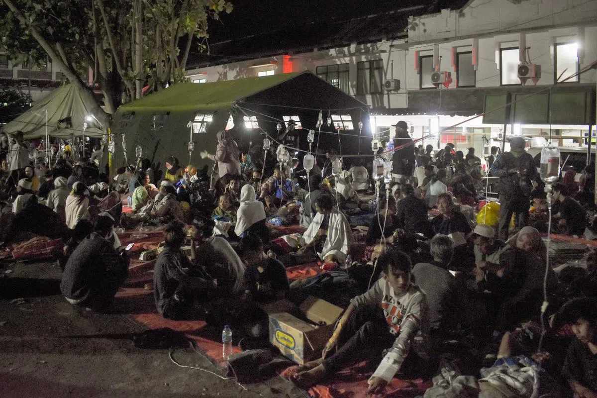 地震中受伤的幸存者21日在一家医院的院子里接受治疗。（法新社）