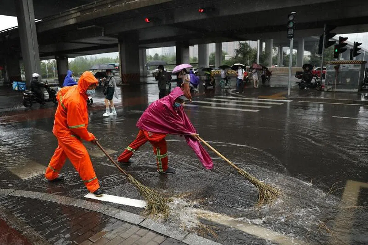 清洁工人们今早高峰时段清除道路积水。（路透社）