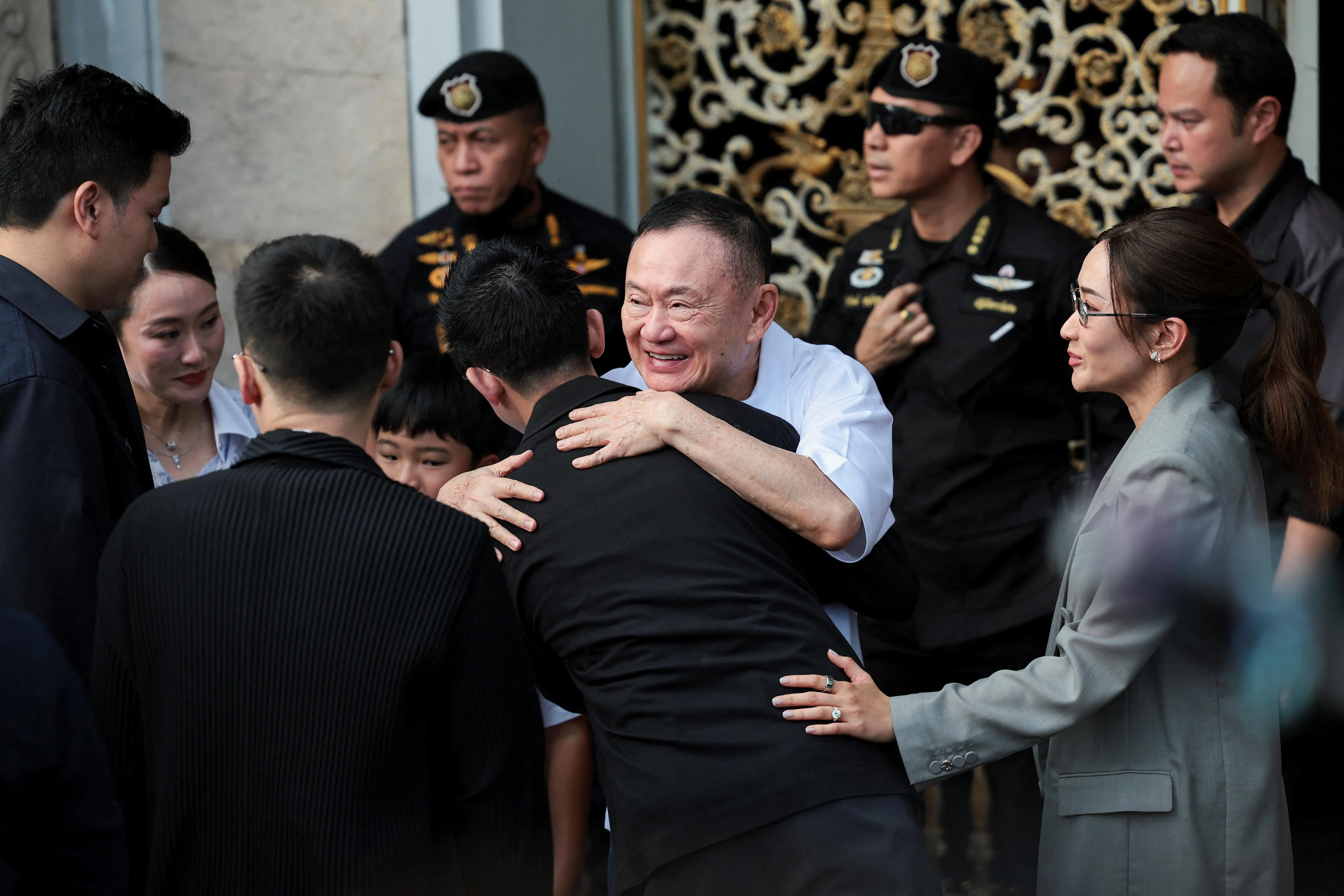 达信在曼谷孔普雷监狱外，与两个女儿——泰国前首相佩通坦（左二）和萍通塔（右一）等亲人一一拥抱。（路透社）