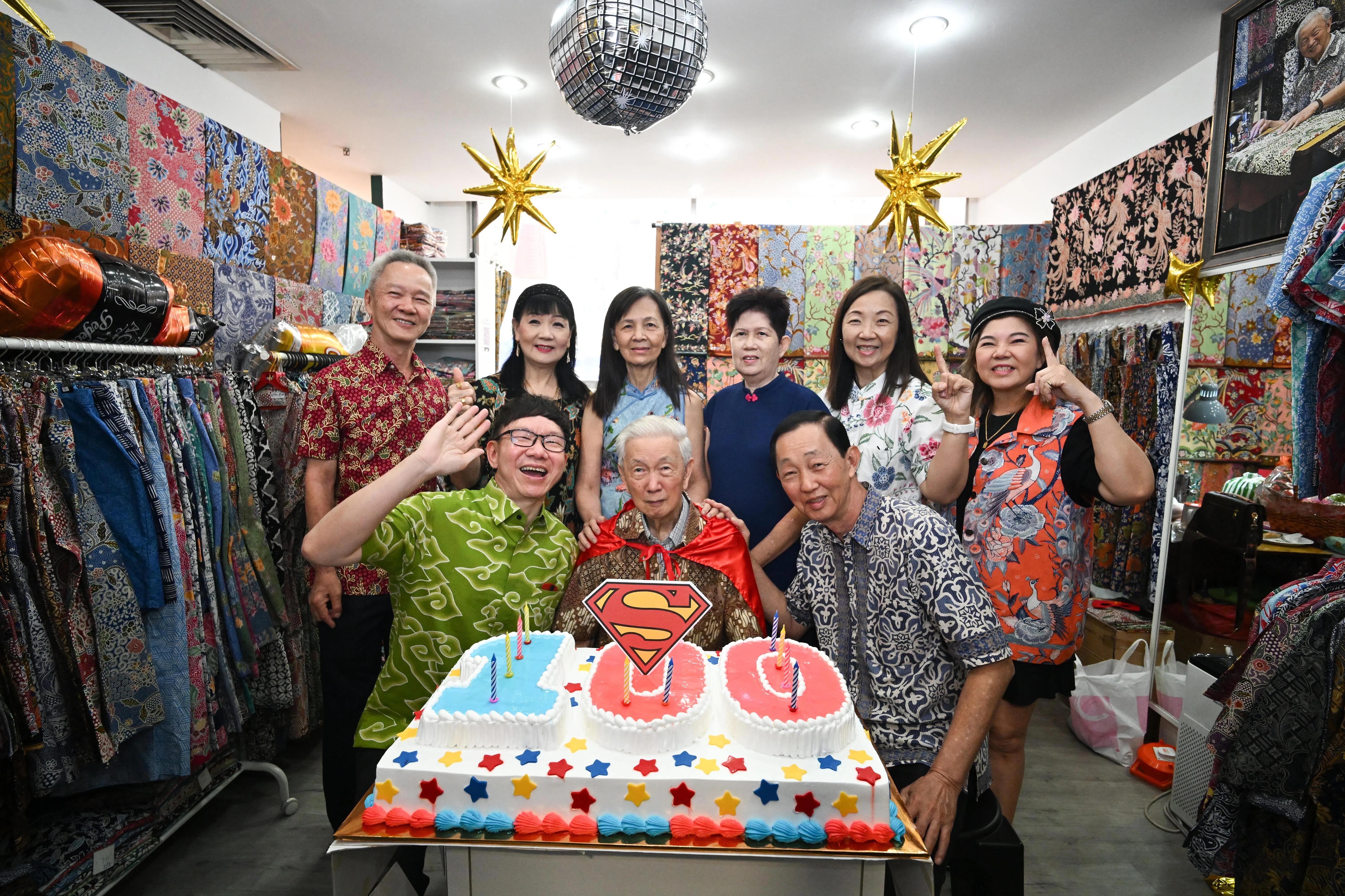 洪甘祥（前排中）于2025年12月13日在自家门店欢庆百岁寿辰。前排左一是洪联通。 （海峡时报）