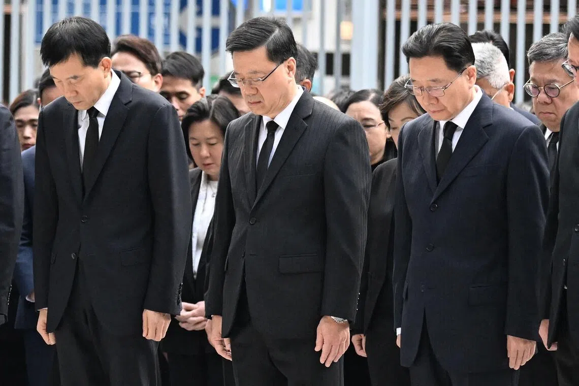 中国港澳办副主任徐启方（左起）、香港特首李家超、香港中联办主任周霁星期六和一众官员，在香港特区政府总部东翼前地默哀三分钟，哀悼在宏福苑火灾中不幸罹难者。（法新社）