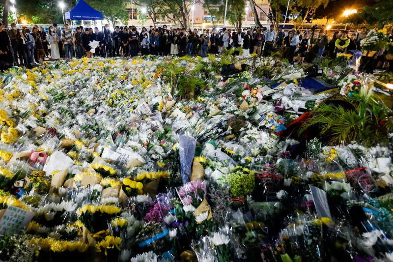 民众12月1日在宏福苑致命火灾后搭建的临时追悼点前聚集，现场堆放着鲜花。（路透社）