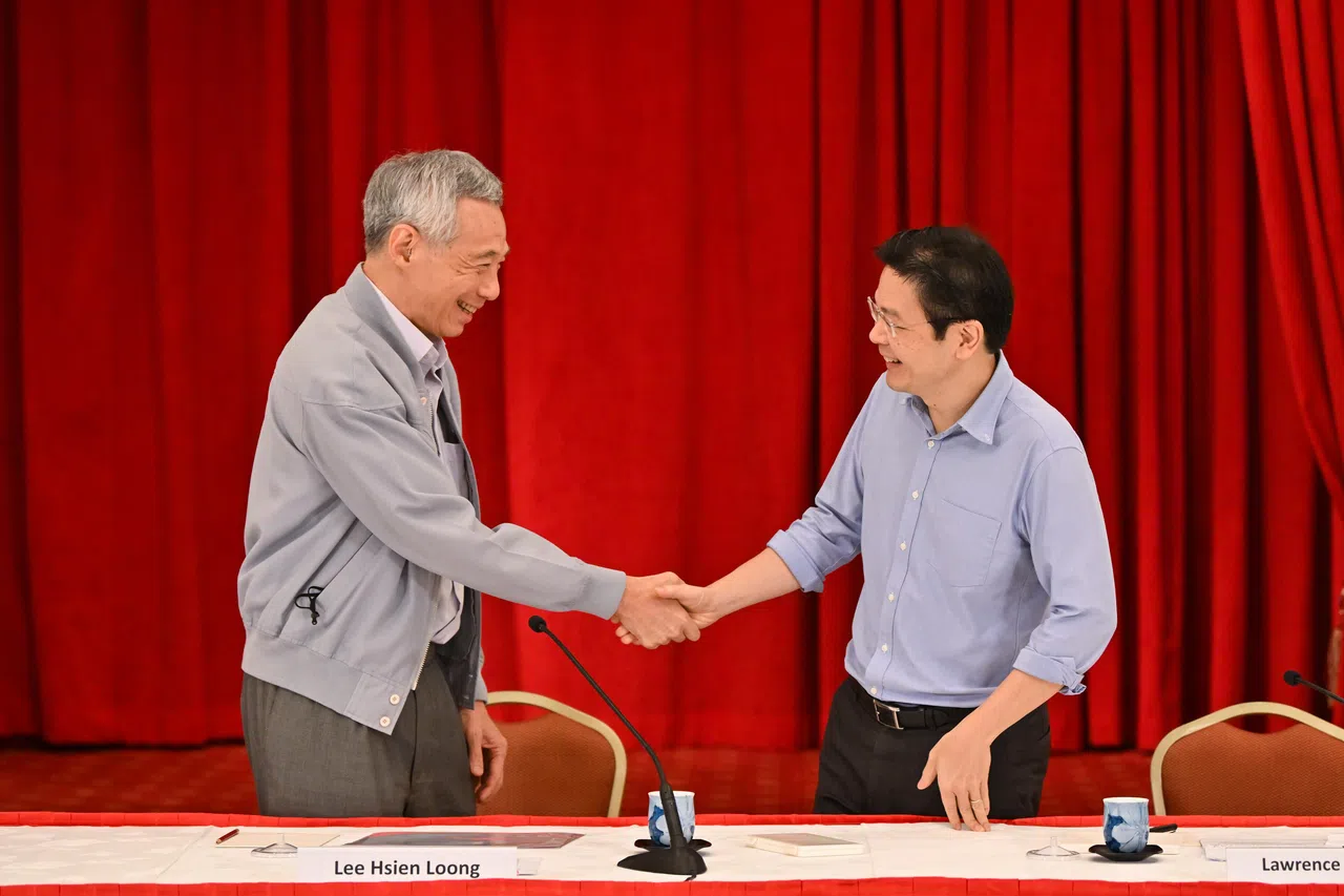 李总理（左）于2022年4月16日在总统府举行记者会，阐述第四代领导人的遴选过程和各方面考量。图为李总理与未来接班人、时任财政部长黄循财在记者会后握手。（海峡时报）