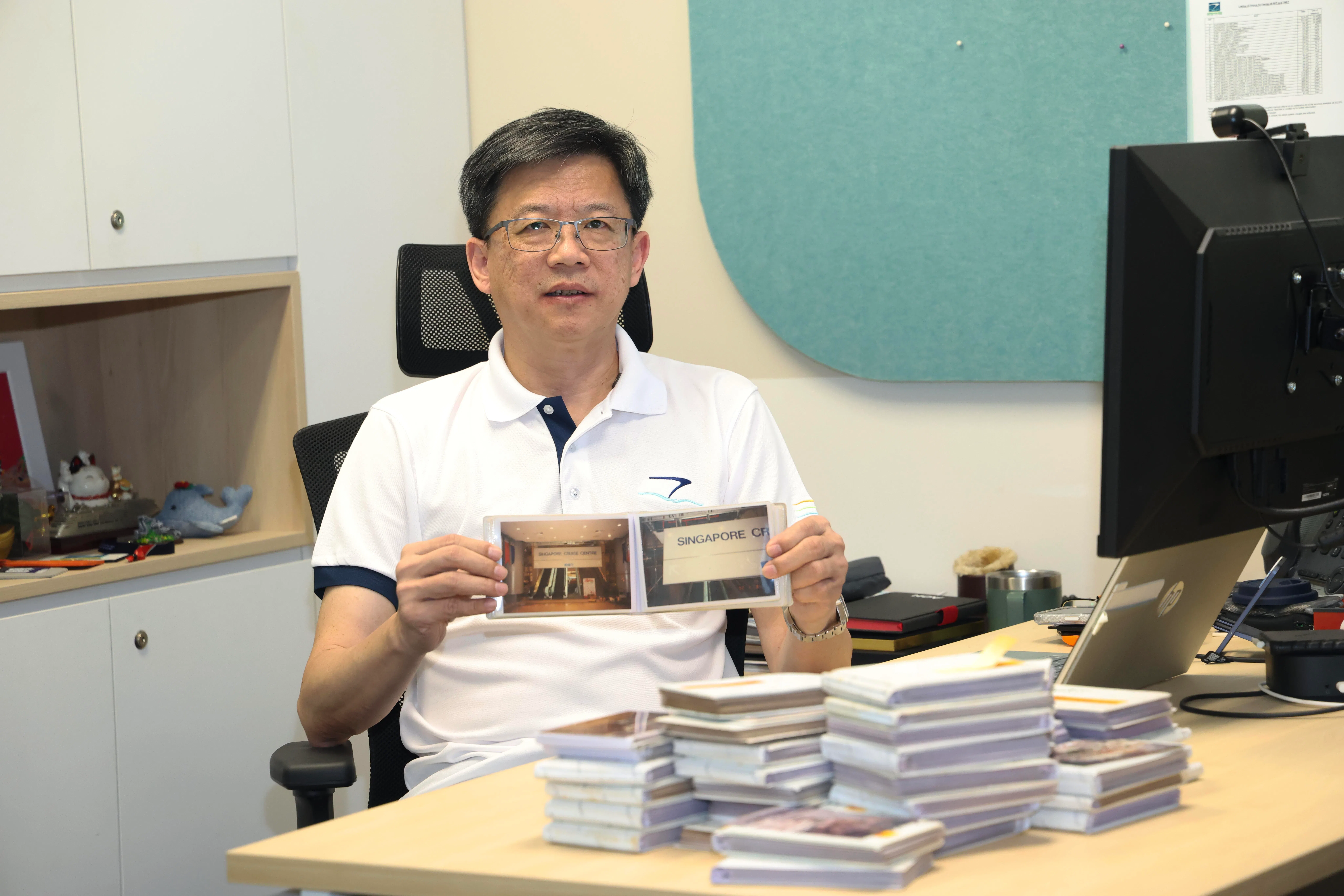 新加坡游轮中心运营副总裁王慕仪对旧码头感到依依不舍，他手中拿着三名前辈留给他的码头旧照。（郑一鸣摄）