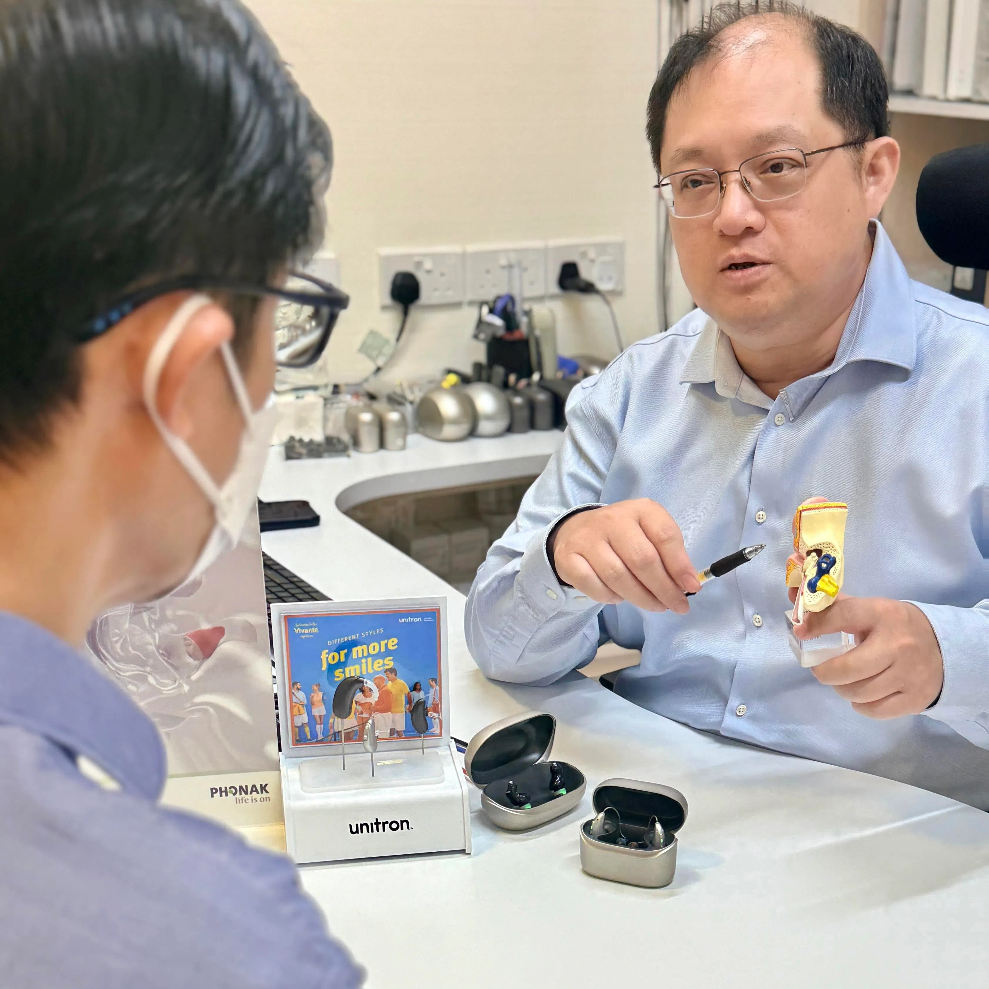 听力学家陈文海（右）为听障者讲解新型助听器技术如何有助于提升生活质量。（受访者提供）