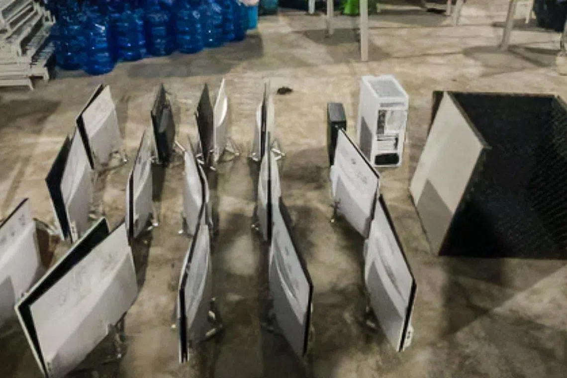 在跨境联合执法行动中起获的证据，包括银行户口和加密货币钱包中的超过250万新元现金，以及53台电子设备、诈骗话术剧本和受害者资料。（新加坡警察部队提供）