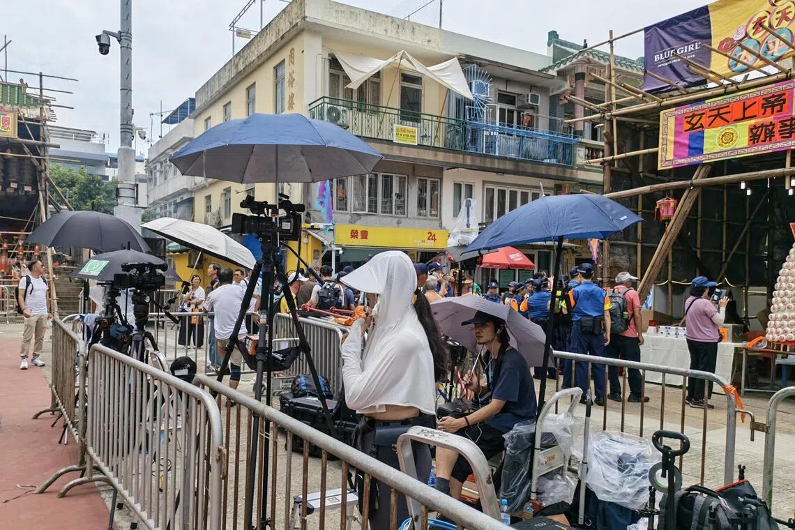 各路媒体在北帝庙前抢“头位”，同时做足防晒措施。（陈爱薇摄）