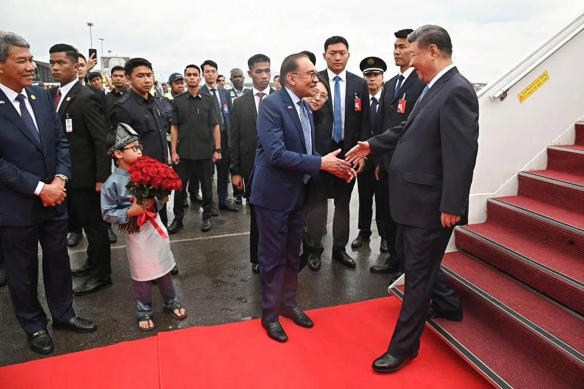 中国国家主席习近平（右一）星期二（4月15日）飞抵吉隆坡。马来西亚首相安华（中）亲自到机场迎接。（法新社）