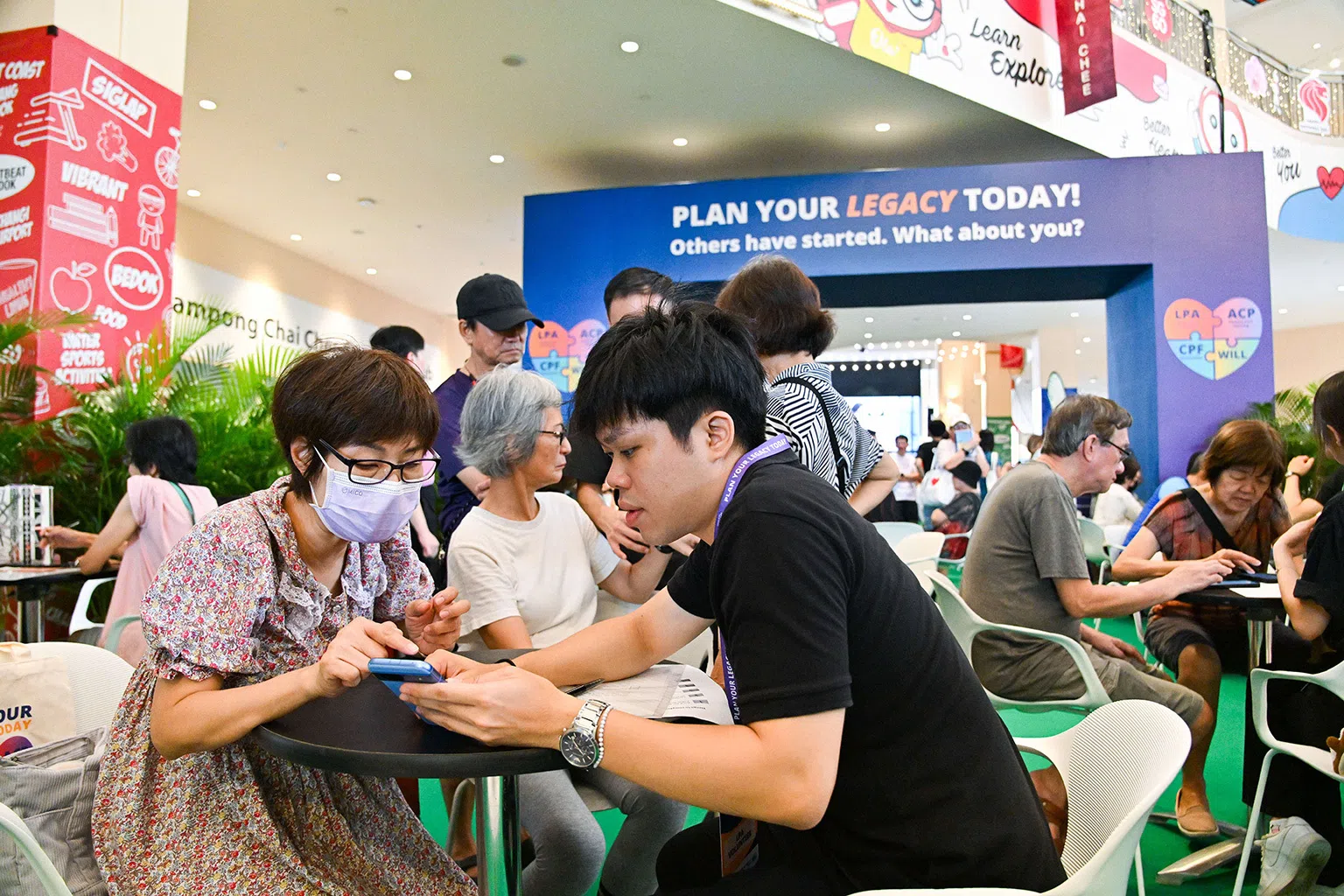 A staff member assists a visitor at an MSF legacy planning event in Singapore, featuring LPA and other planning tools.