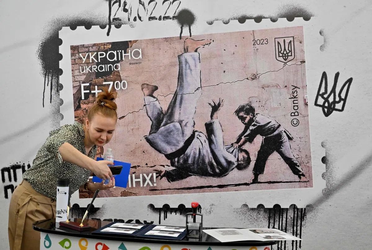 英国街头艺术家班克斯在乌克兰首都基辅一座被炸毁建筑的墙上，画了小男孩用柔道击败成年男子的壁画，象征以弱胜强，也影射热爱柔道的俄罗斯总统普京。乌克兰发行了一款以这幅壁画为图案的邮票，还在邮票下方加上“去死吧普京”的字样，吸引许多市民到邮局拍照。（法新社）