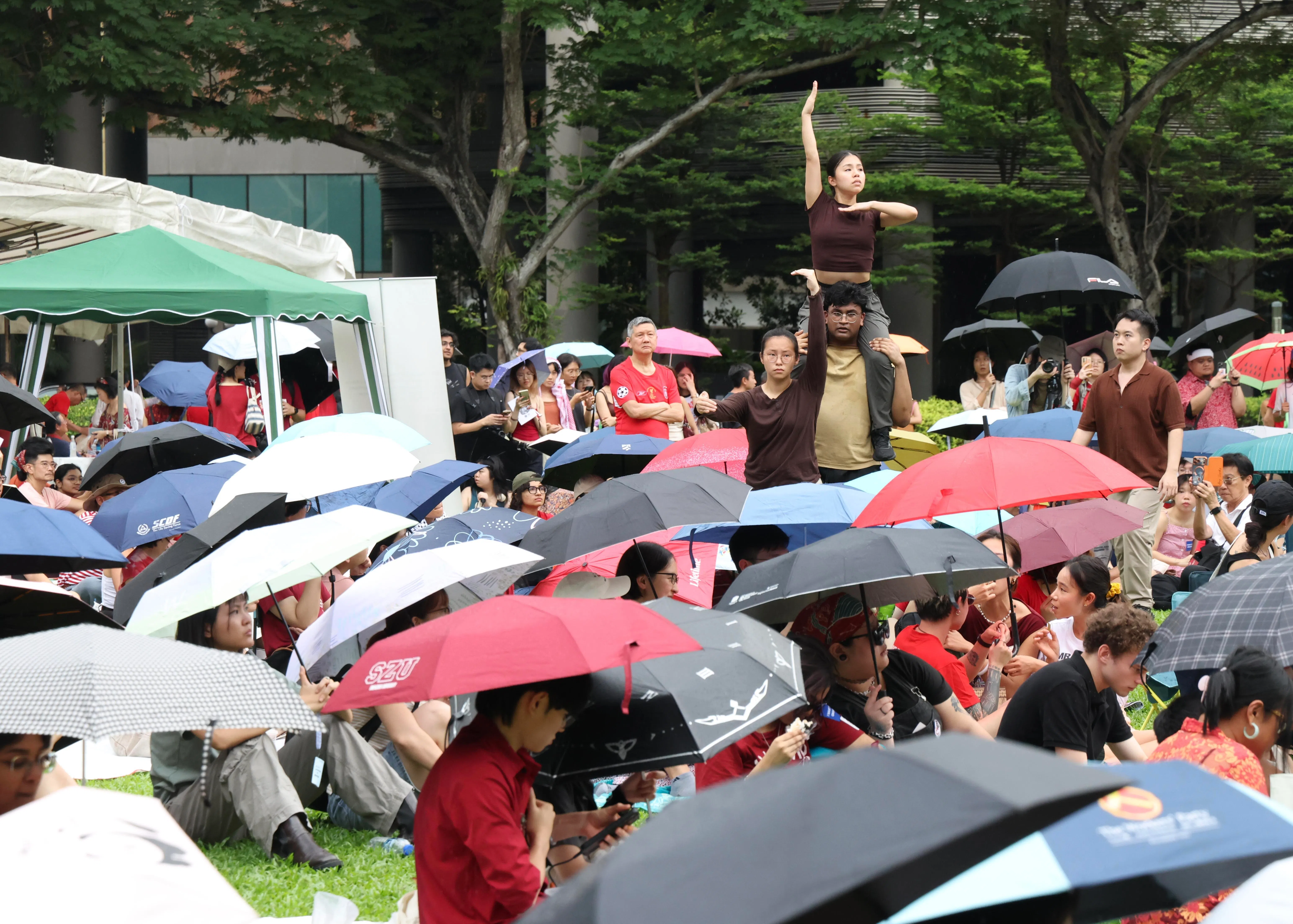 集会进行时一度下雨，但参与者没有离席，纷纷拿出雨伞遮雨。（郑一鸣摄）