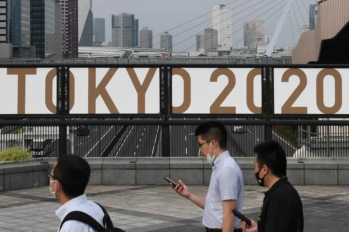 7月7日，几名民众在东京台场路过一个印有“东京2020”的告示牌。（法新社档案照）