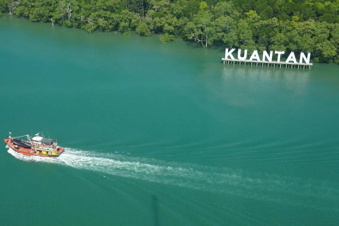一艘渔船正缓缓驶过标志性的“KUANTAN”大字招牌。关丹不仅有迷人的河岸风光，更是通往古老红树林探索之旅的起点。（彭亨旅游局官网）