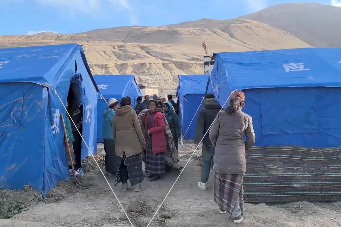 人们聚集在地震后临时搭建的避难所旁边。（路透社）