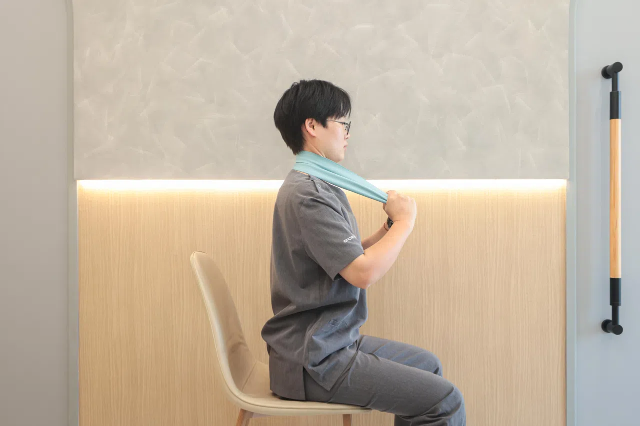 弹力带中间部分搁在颈部后下方。（李冠卫摄）