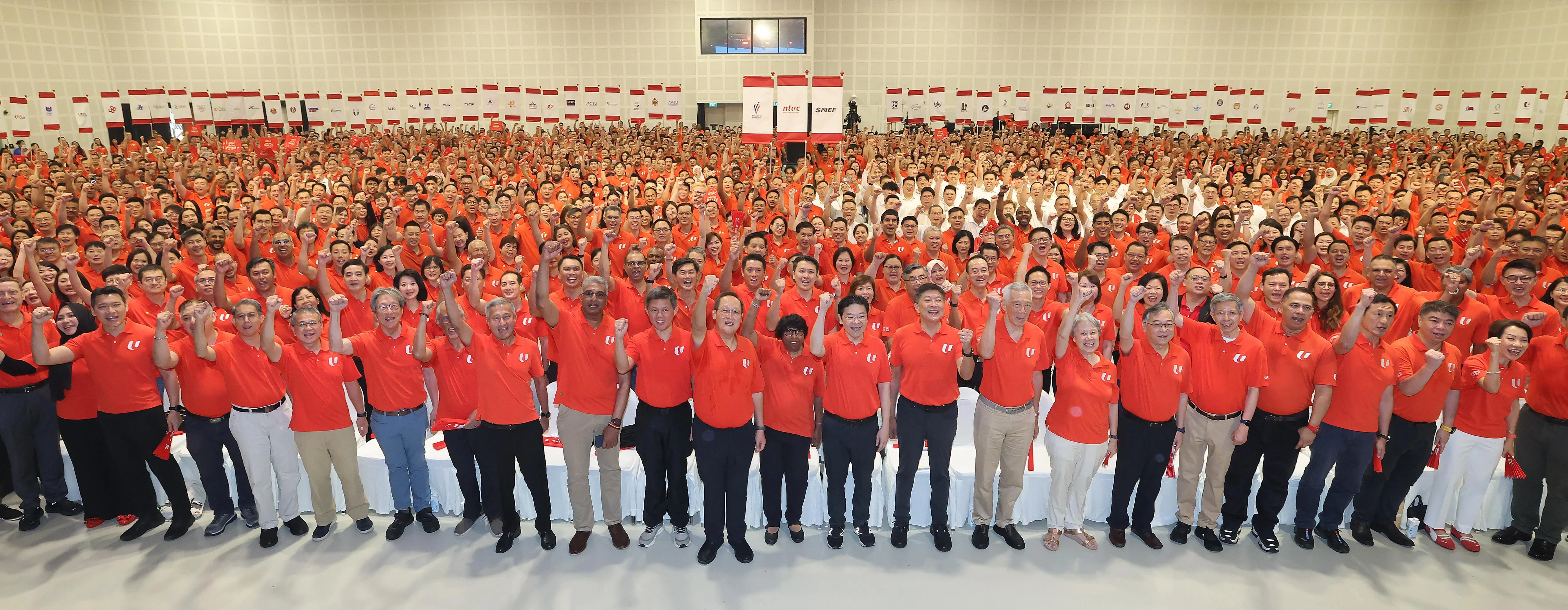 五一劳动节集会星期五在白沙乐怡度假村举行，出席者包括文化、社区及青年部代部长兼教育部高级政务部长梁振伟（左三起）、职总副会长林德泉、主管回教事务代部长兼内政部高级政务部长费绍尔副教授、律政部长兼内政部第二部长唐振辉、全国职工总会前秘书长林瑞生、社会及家庭发展部长马善高、外交部长维文医生、职总财务秘书杜莱沙米、公共服务统筹部长兼国防部长陈振声、人力部长陈诗龙医生、职总会长丹娜乐芝米、黄循财总理、职总秘书长黄志明、国务资政李显龙与夫人何晶、副总理兼贸工部长颜金勇、全国雇主联合会会长陈启德、职总副会长阿都沙曼、社会政策统筹部长兼保健卫生部长王乙康、职总副会长林志康，以及永续发展与环境部长傅海燕。大合照后方正中央的三面旗帜，分别是人力部（左起）、职总和雇联的旗帜，代表劳资政三方合作伙伴；左右两边则是职总附属工会、附属协会、社会企业和相关组织的会旗。（唐家鸿摄）