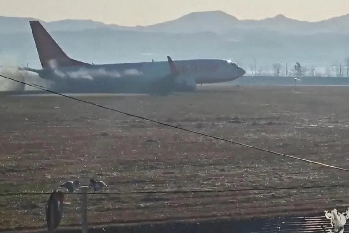 视频截图显示，济州航空客机冲出跑道时机腹贴地冒着黑烟。（路透社）
