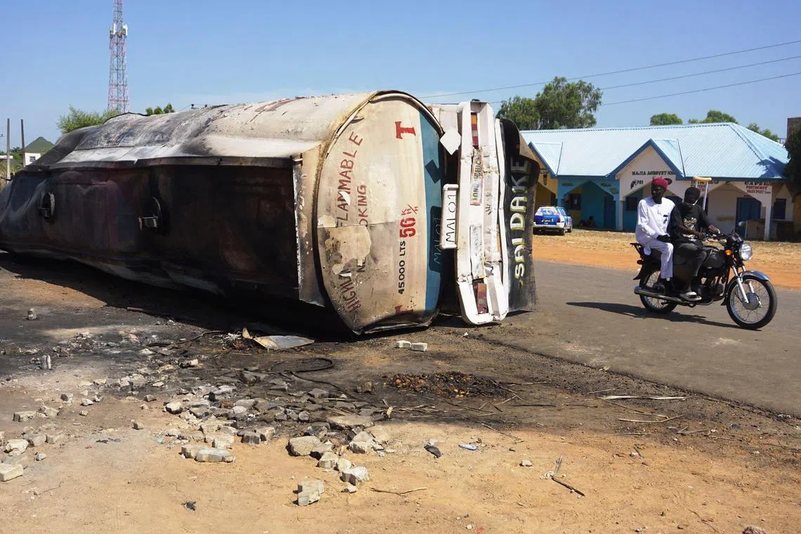 尼日利亚北部吉加瓦州一辆油罐车日前失控翻车，造成至少140人死亡。图为一辆电单车驶过这辆油罐车的残骸。（法新社）