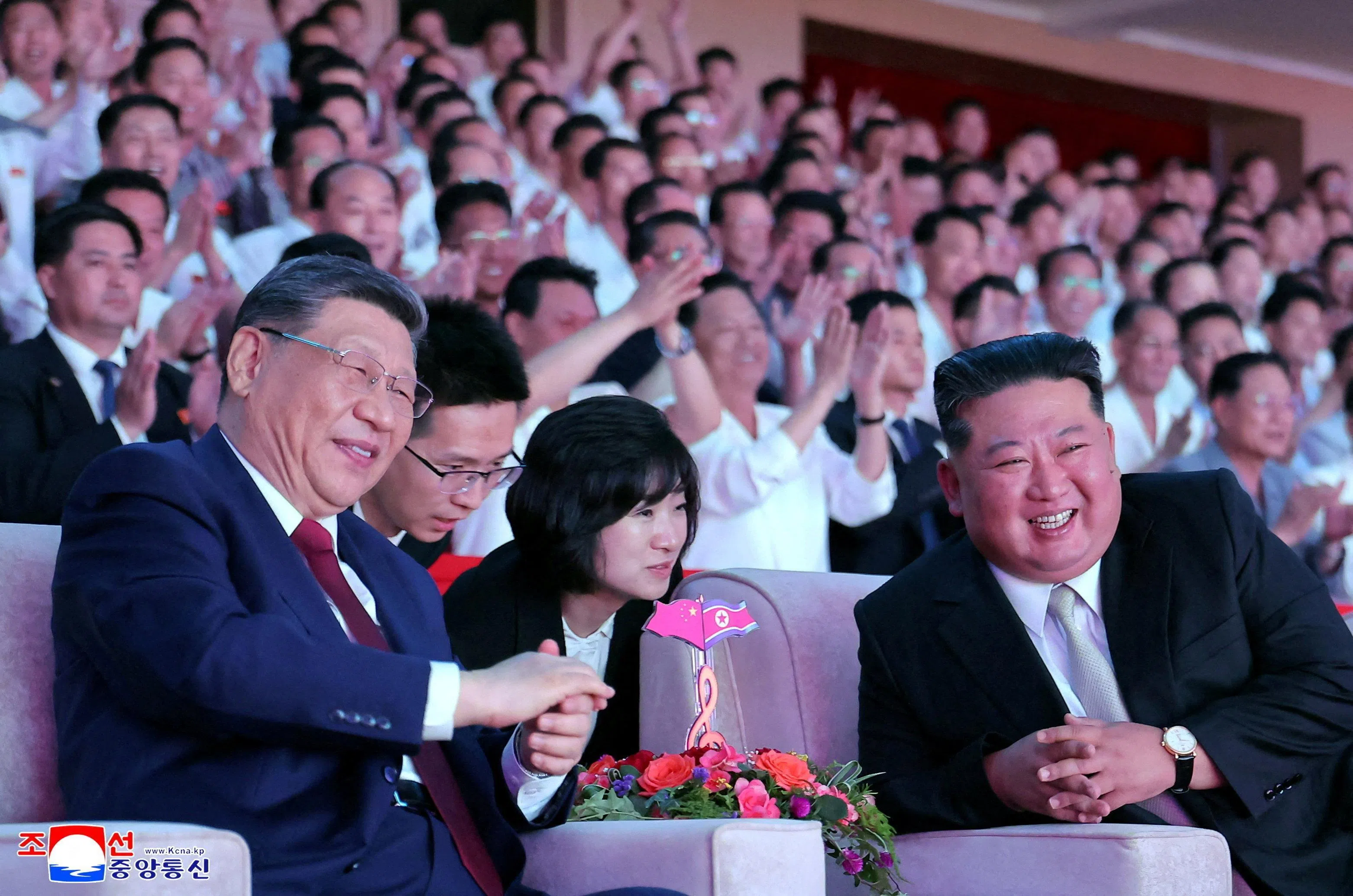 习近平和金正恩在观看演出时，面带笑容交谈。（路透社）