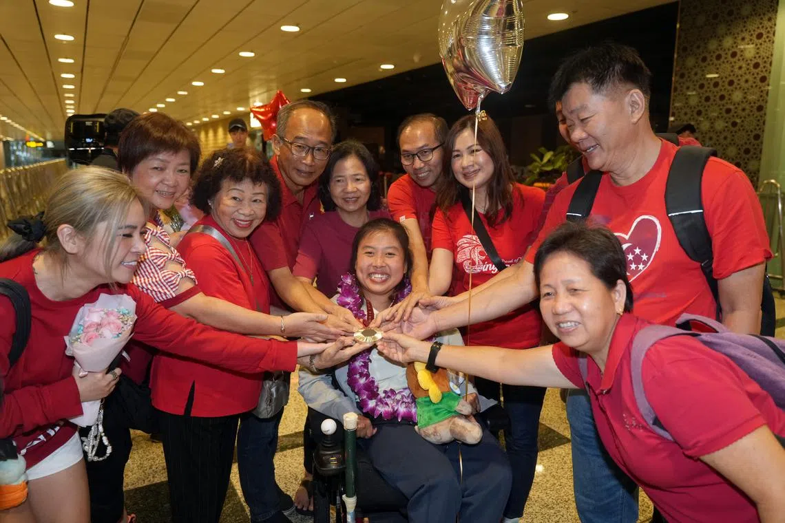 陈仪婷的家人和亲戚一同拿起她的历史性银牌沾喜气。左二为她的母亲吴玲梅，左四为她的父亲陈文嘉。（谢智扬摄）