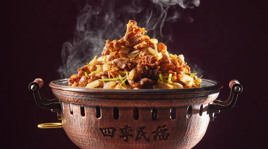 精品贝勒烤肉将羊后腿肉与大葱爆炒，盛在运自北京的传统铜器内。（餐馆提供）