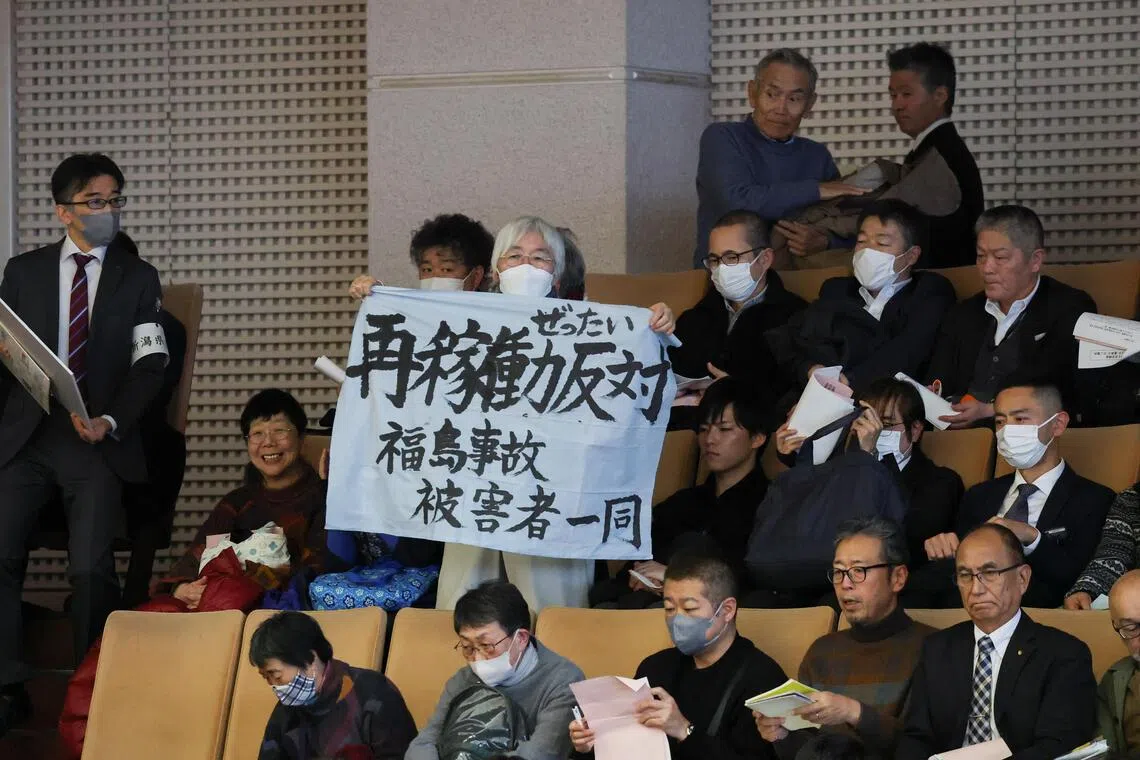 在新潟县议员投票当天，一名女子在旁听席举着一条写有“反对重启”字样的横幅。（路透社）