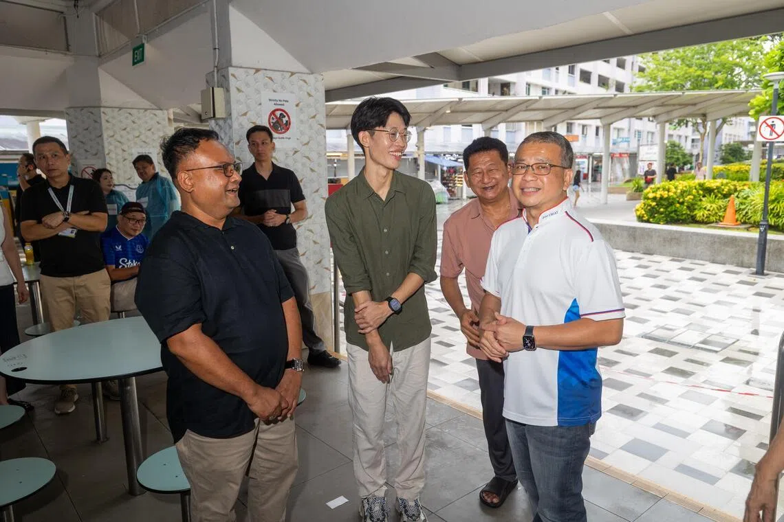 负责东海岸集选区的律政部长兼内政部第二部长唐振辉（右一），星期一（5月18日）到第216座巴刹与熟食中心视察清洁消杀工作，并和小贩代表了解情况。（吴先邦摄）