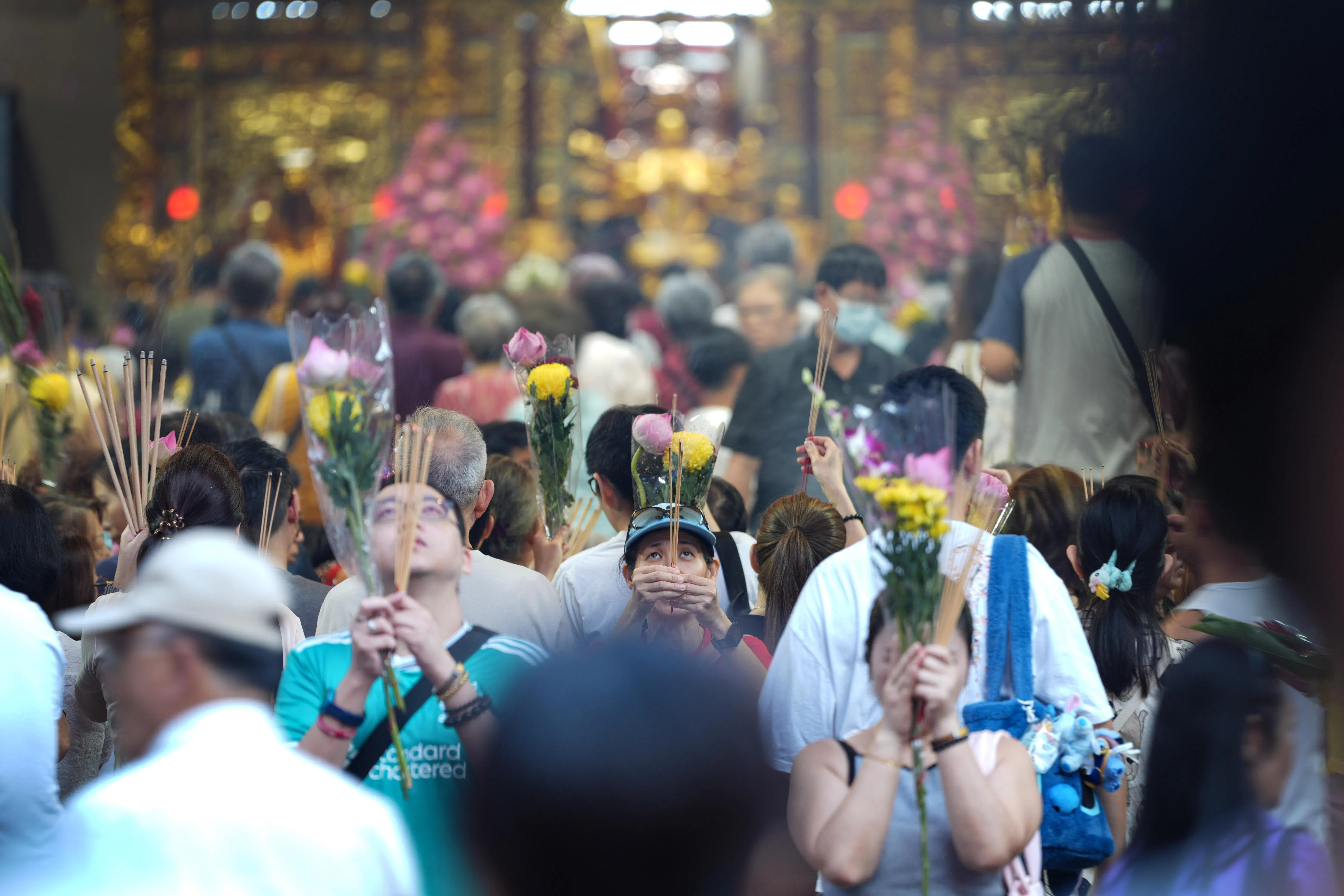 观音堂内，信徒手持鲜花和香烛，神情虔诚。（何家俊摄）