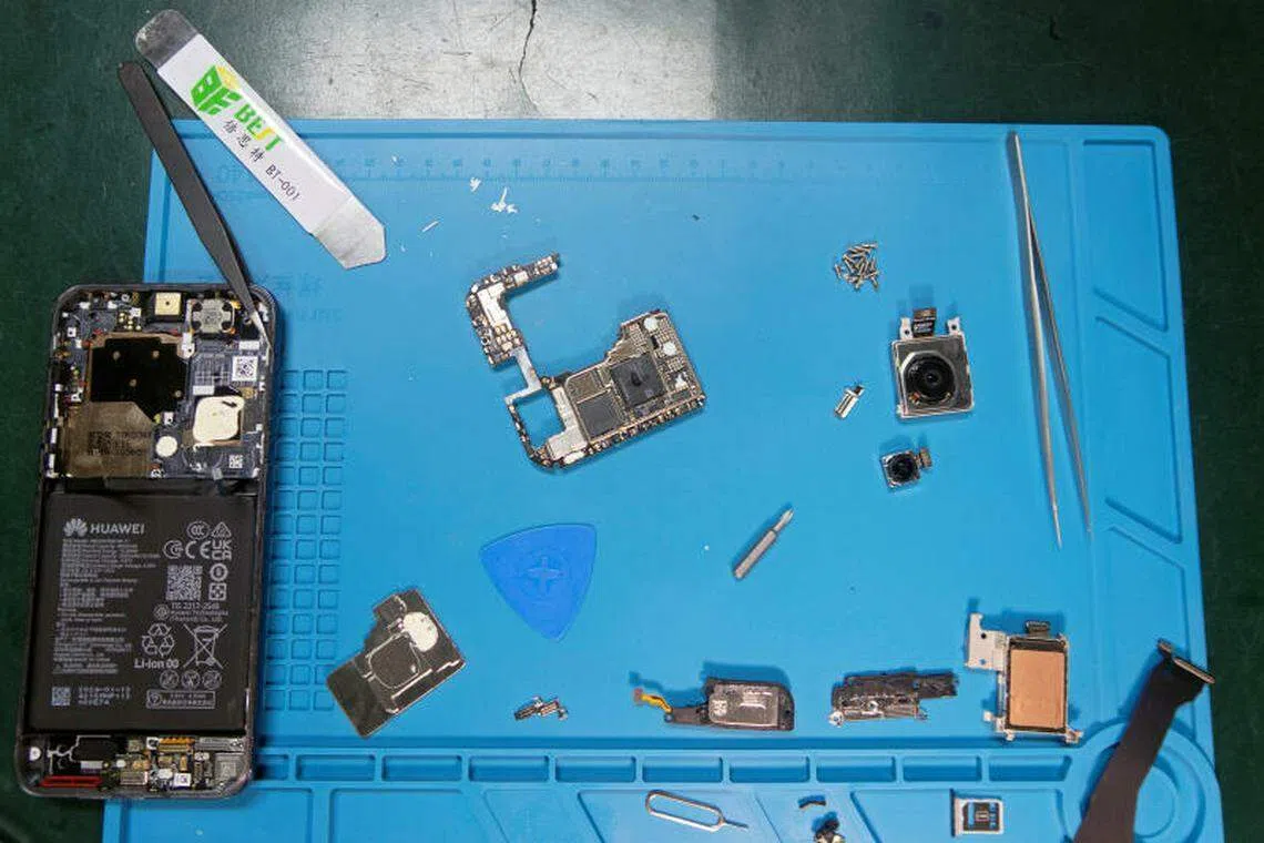 在线技术维修公司iFixit的工作人员拆解华为Pura 70 Pro后，将其内部组件摆放在桌子上。（路透社）